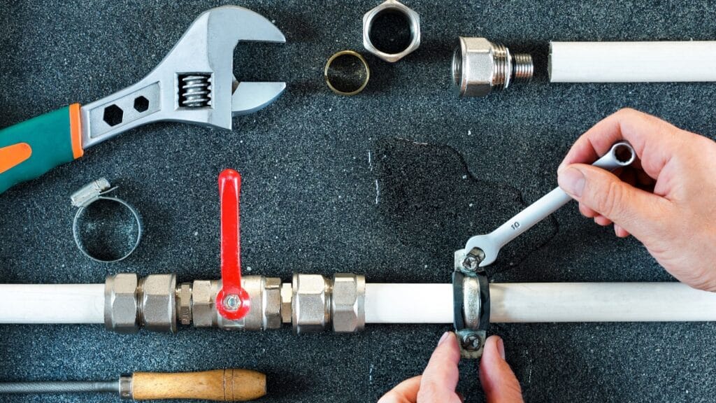 Plumber repairing a pipe valve with an adjustable wrench in Murrieta