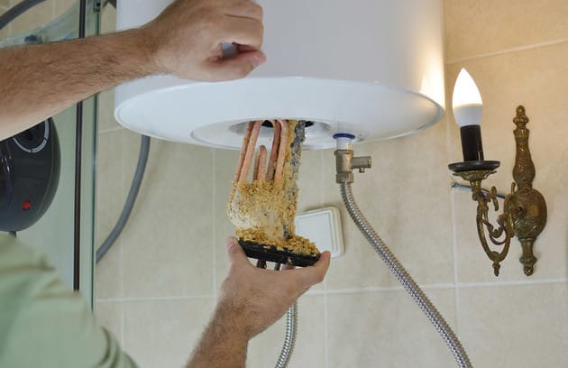 Technician removing mineral buildup from a water heater in Murrieta