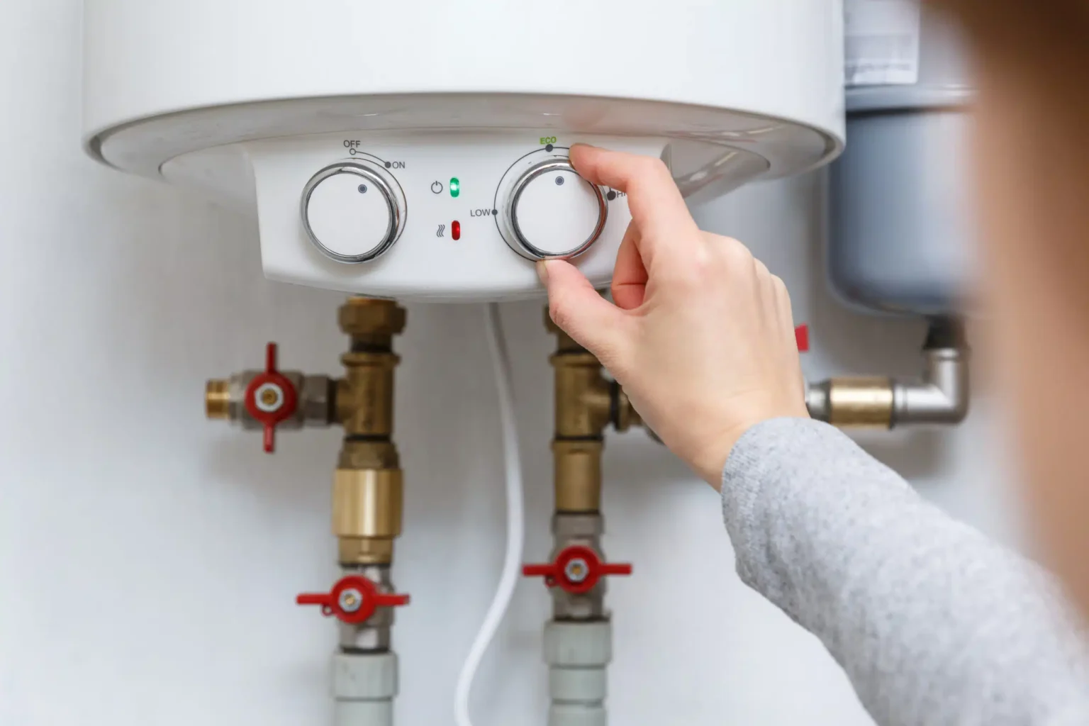 Homeowner adjusting the temperature controls on a water heater in Murrieta